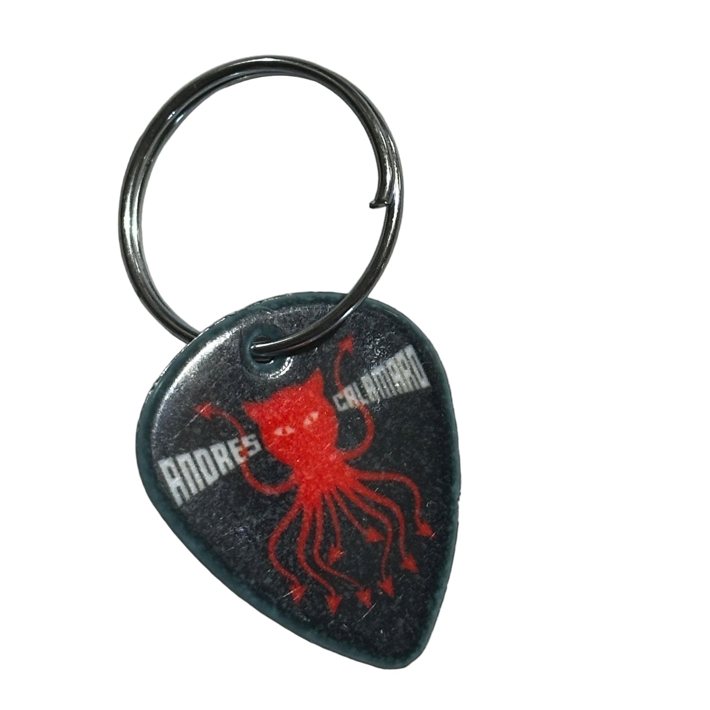 Andres Calamaro Guitar pick-shaped keychain with red design on a gray surface